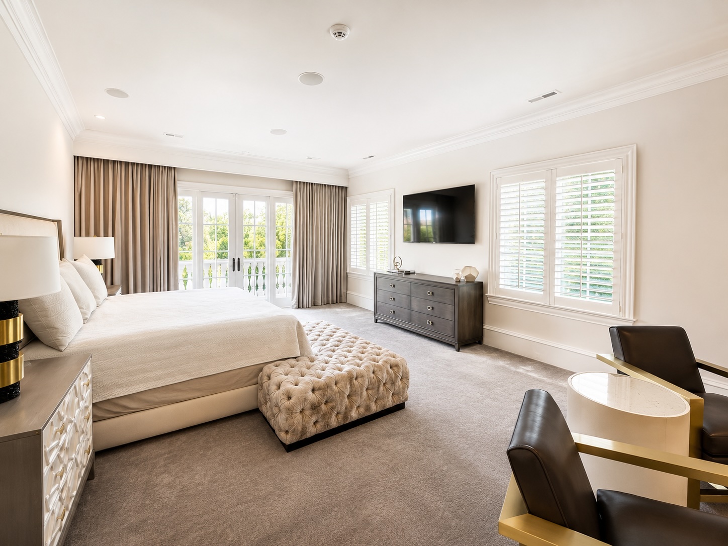 Primary bedroom with French doors opening to a private balcony overlooking the pool