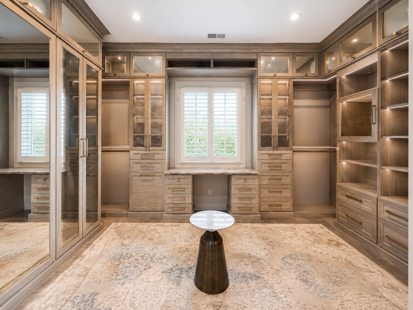 Her walk-in dressing room with custom millwork, island, and chandelier