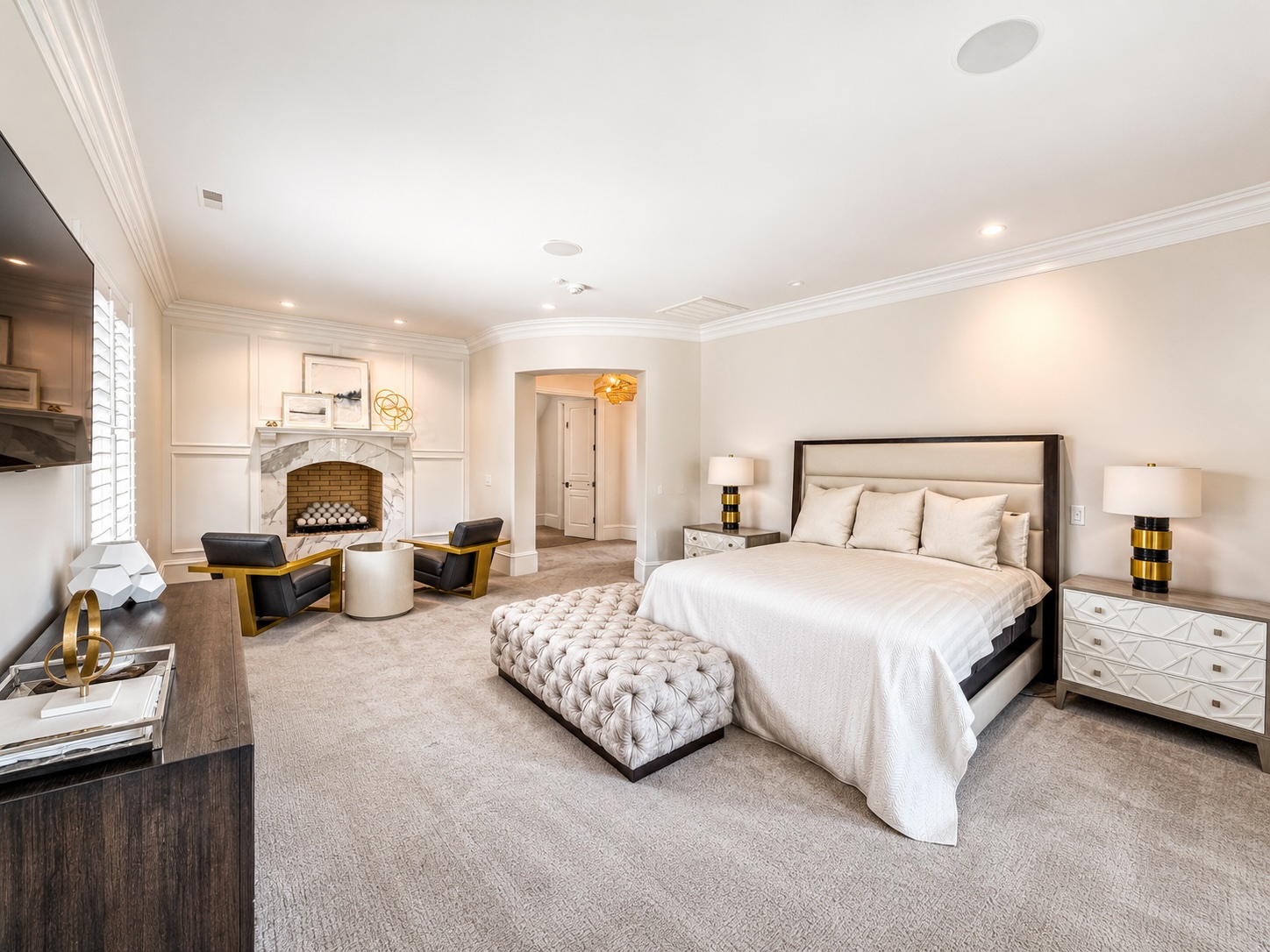 Primary bedroom with marble fireplace, sitting area, and coffered ceiling