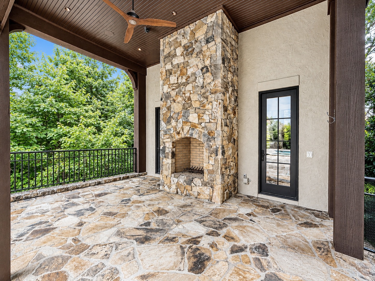 Pool house loggia with stone fireplace, timber beams, and flagstone floor