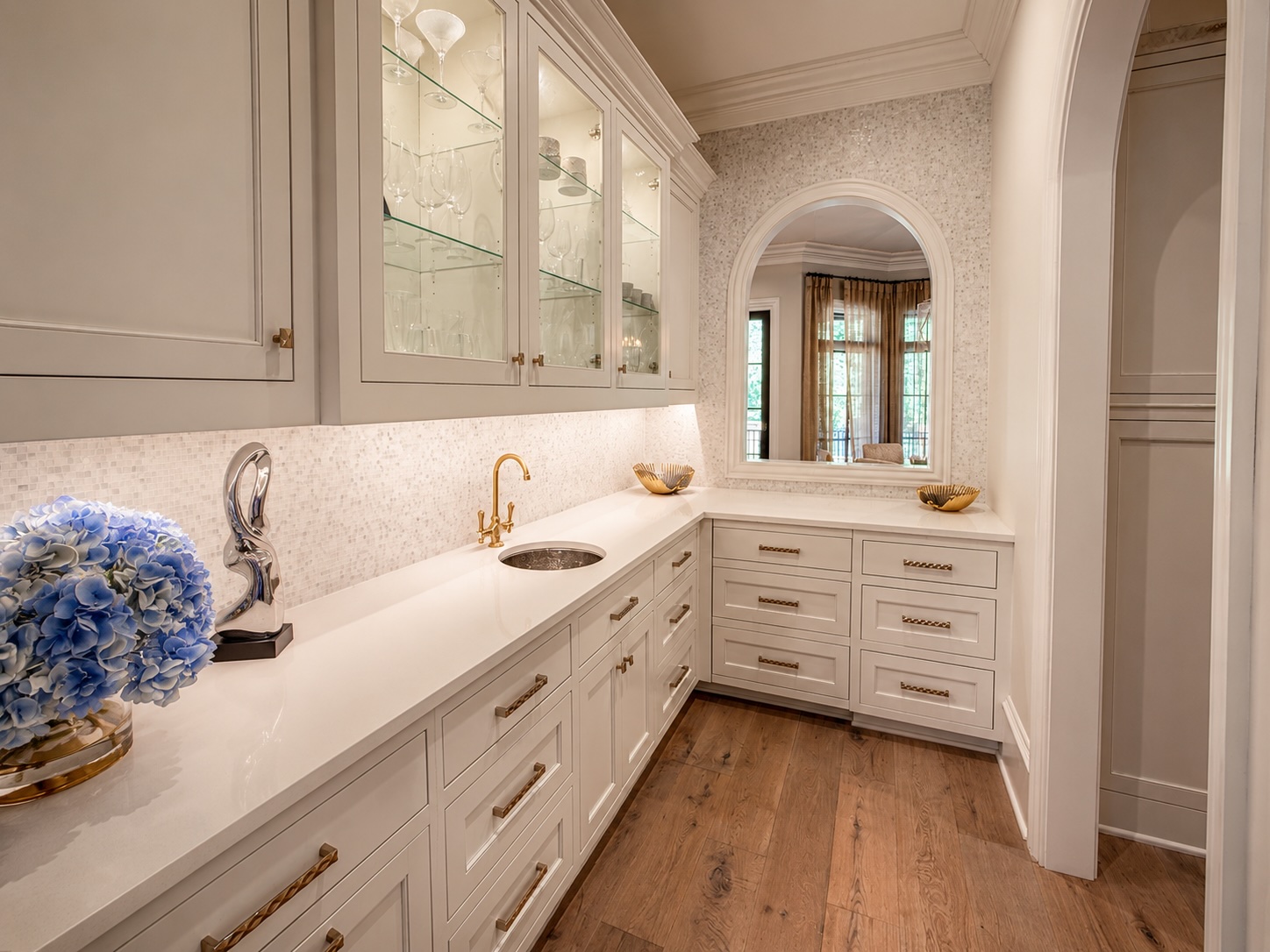 Butler's pantry with brass hardware, marble backsplash, and glass-front cabinetry