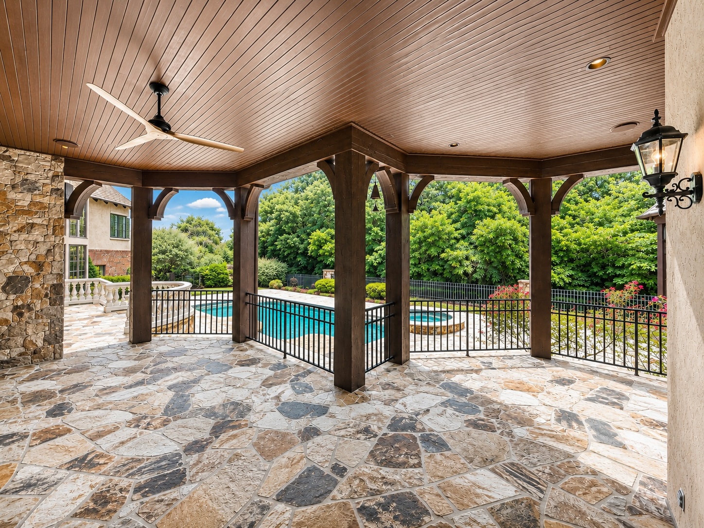 Covered rear porch with timber beams and flagstone floor overlooking the pool and golf course