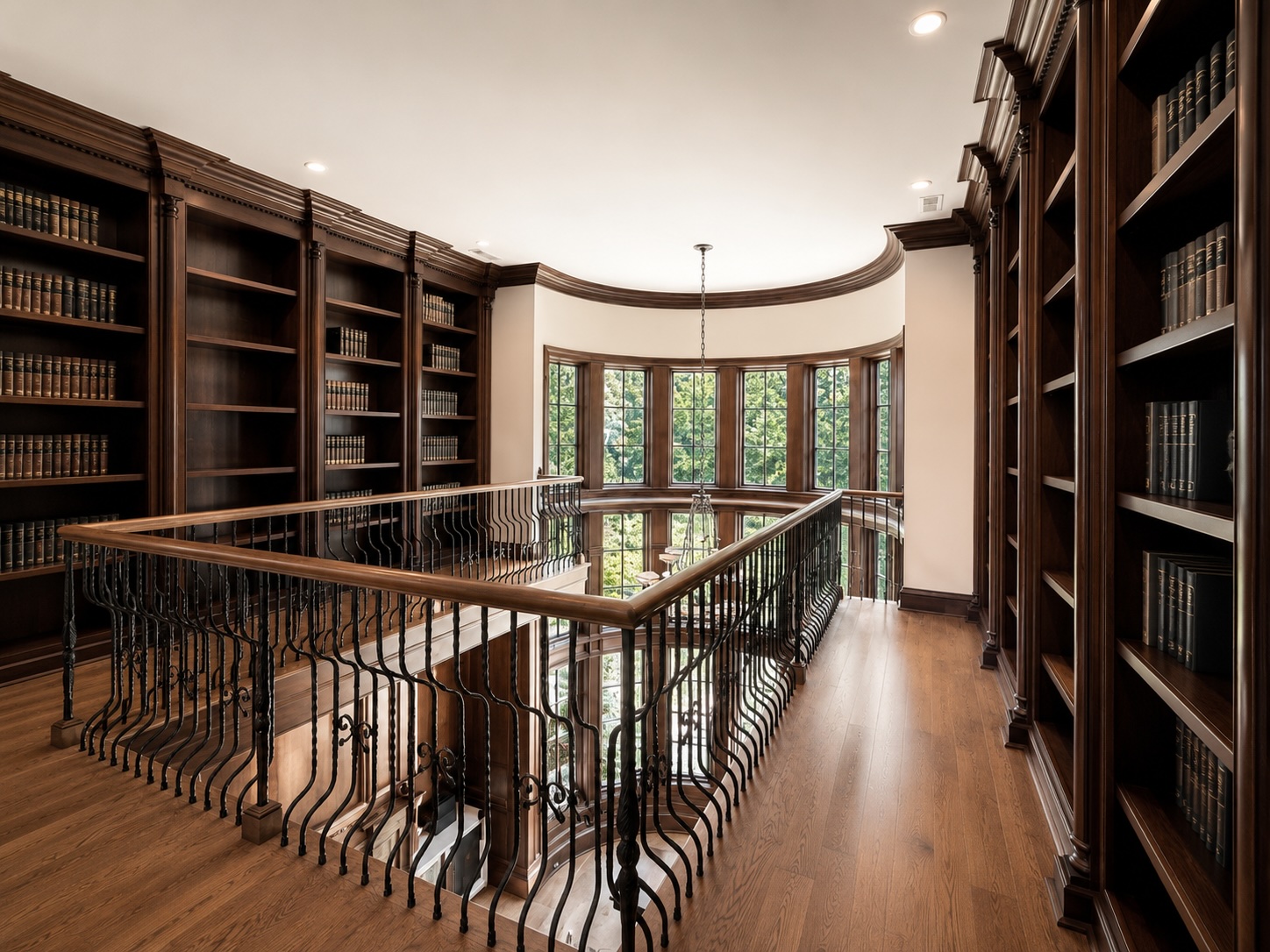 Upper library mezzanine with walnut bookcases and wrought-iron balustrade