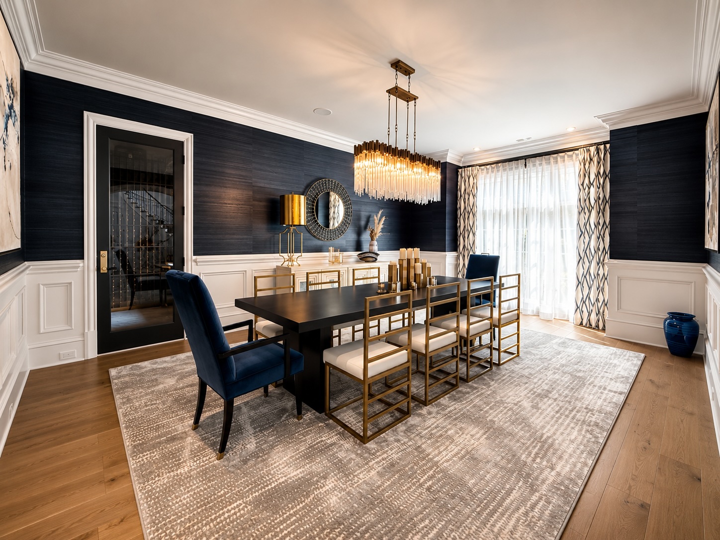 Formal dining room with navy grasscloth walls, crystal chandelier, and paneled wainscoting