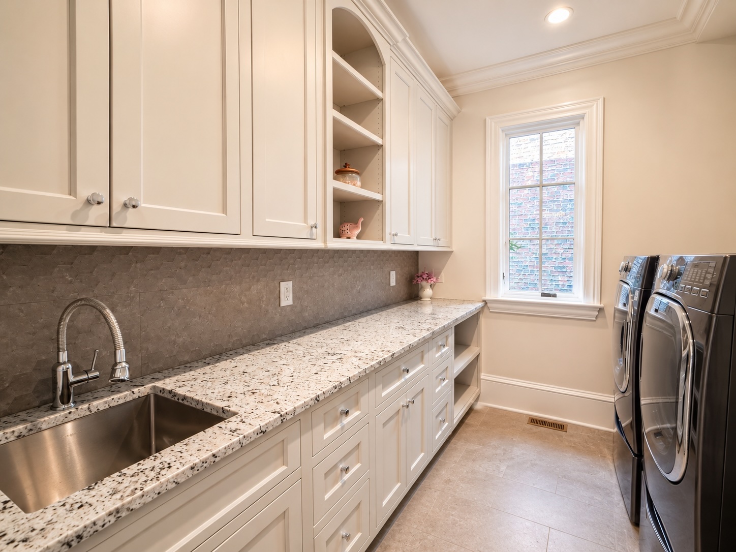 Main-level laundry room with granite counters, custom cabinetry, and dual washers