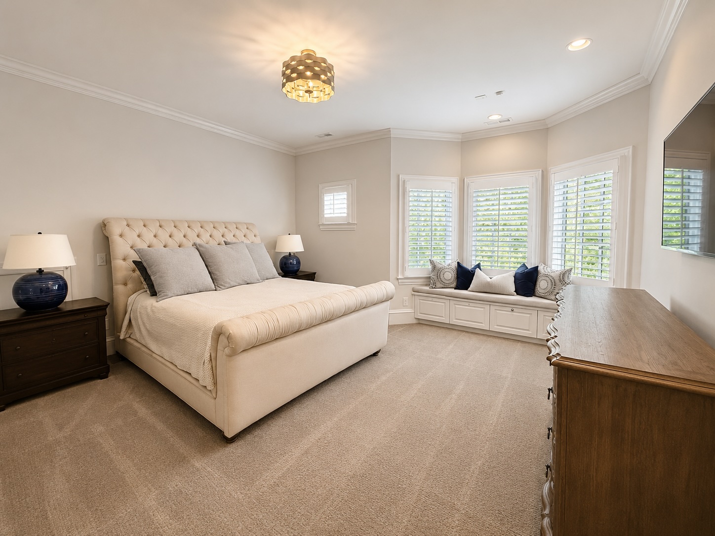 Guest suite with tufted sleigh bed, sitting area, and custom drapery